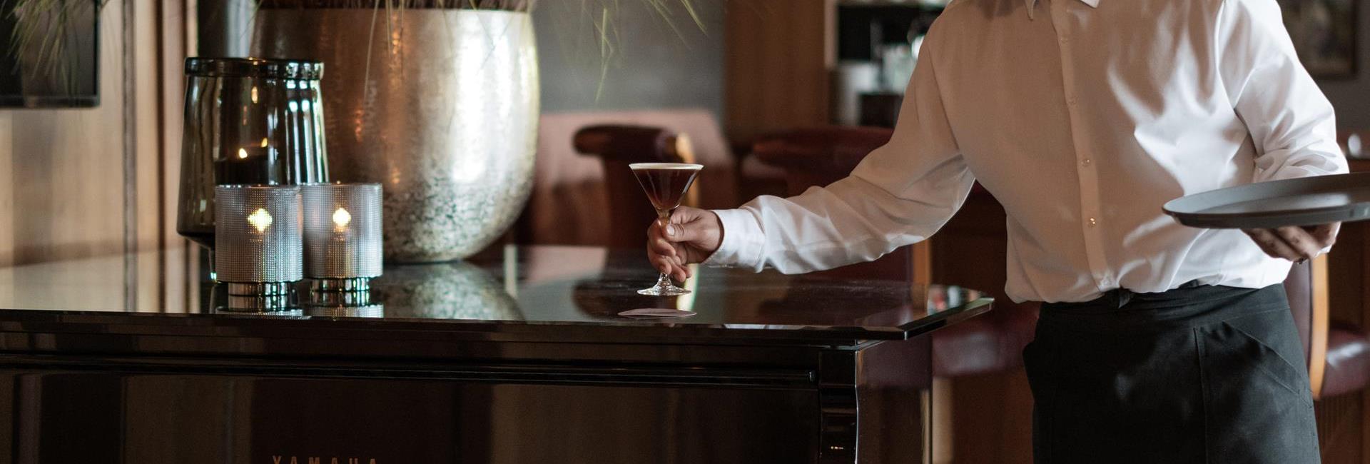 A waiter is serving a cocktail